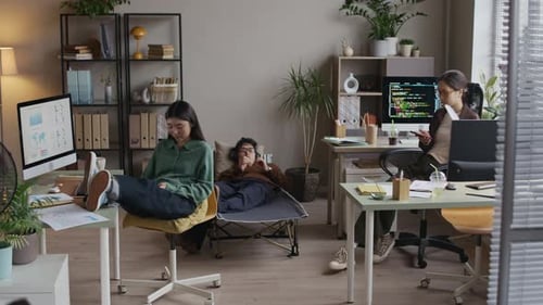 Des collègues détendus faisant une pause avec les appareils numériques dans un bureau de démarrage