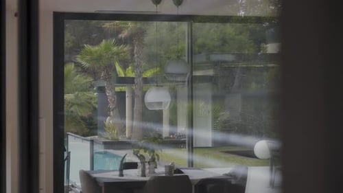 Slow motion shot of electric blinds opening on large glass windows at a villa