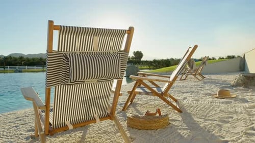 Pillow from one of the luxurious beach chairs flutters back and forth in the wind on a small sandy b