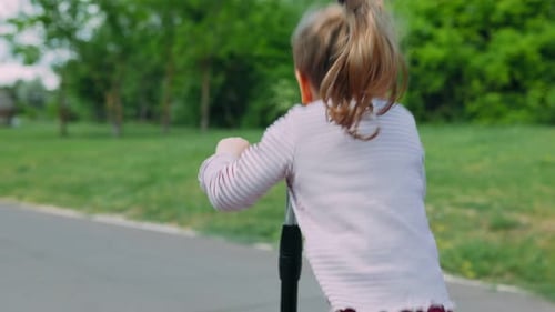 Girl Riding Scooter in the Park on Sunny Day