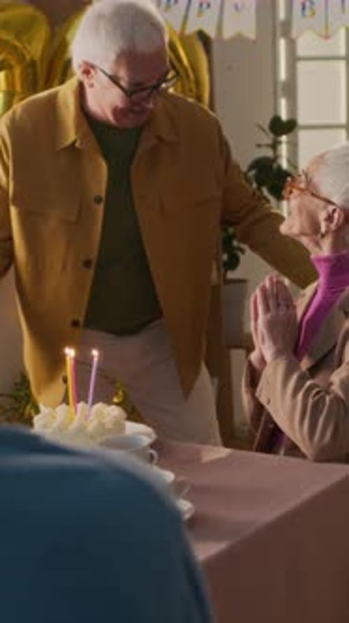 Senior Woman Receives Birthday Cake from Husband Indoors