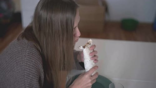 Woman Eating Delicious Wrap Sandwich Eating Lunch Meal in Cozy Home Environment