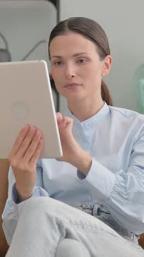 Woman Using Tablet with Unhappy Expression Indoors
