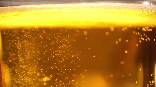 Extreme Close up of craft Beer bubbles floating to the top of a pint glass with foam