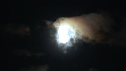 Moon behind clouds in the dark night sky