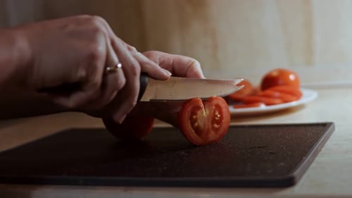Hands Slice Fresh Tomatoes in Kitchen