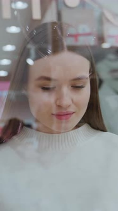 Young Lady Looking at Display with Reflections in Glass in Mall