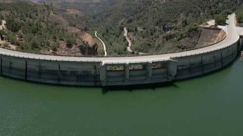 Car driving on a road in a dam. Aerial overhead view of road over curved dam. Spain.