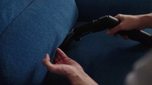 Person Cleaning Couch with Portable Machine Close Up