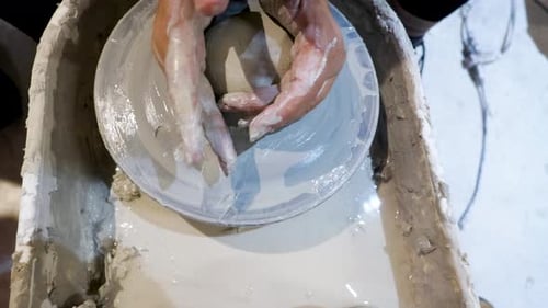 overhead close view of an African American hands spinning clay very sporadically