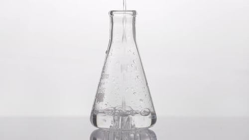 Expérience en laboratoire avec une fiole Erlenmeyer — versement d'un liquide transparent