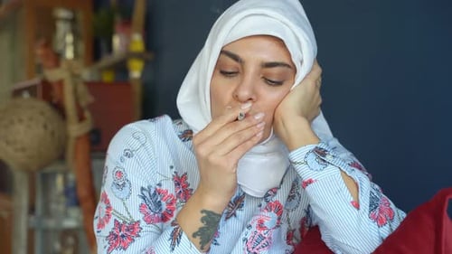 Woman Wearing Headscarf Smoking a Cigarette Indoors
