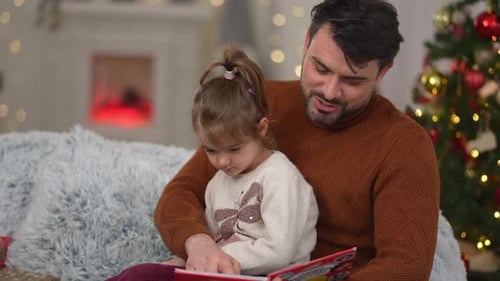 Father and Daughter Reading Christmas Storybook Together