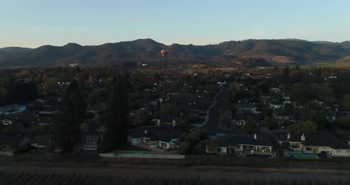 Aerial of Hot Air balloon flying over small town during sun rise