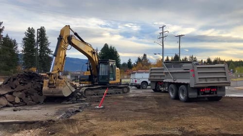 Excavator Hard at Work Filling Dump Truck with Asphalt Waste at Building Site in British Columbia, C