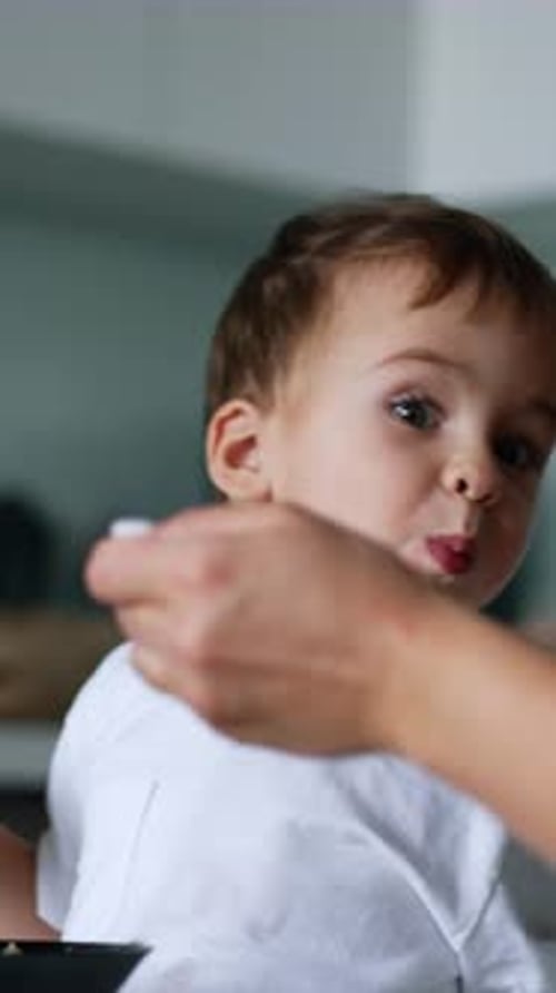 Adorável criança caucasiana sentada à mesa segurando um pedaço de pão.