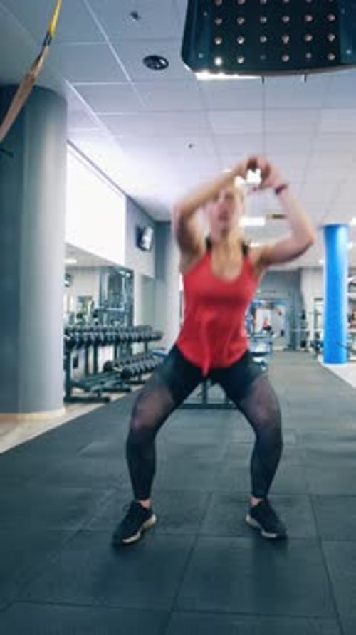 Active young female at fitness center. Front view of a woman in sportswear doing workout confidently