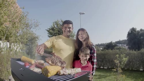 Happy Man Standing at Barbecue Grill with Son and Daughter