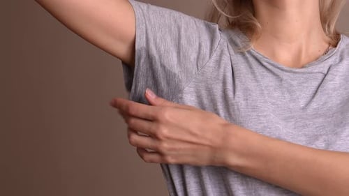 Close-up of woman with sweating hyperhidrosis with sweat stain on clothes