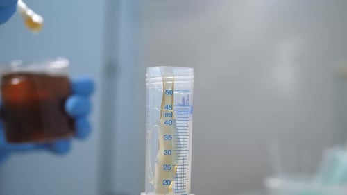 Closeup of a Laboratory Assistant Pouring Honey Into a Test Tube in a Laboratory