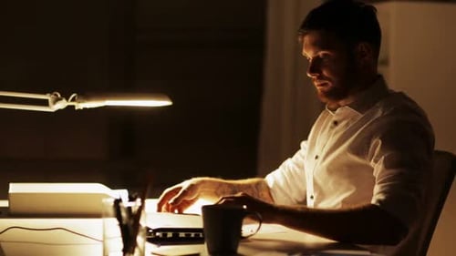 Man Works Late at Desk on Laptop Computer