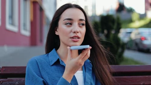 Young Woman Sending a Voice Message on a City Street