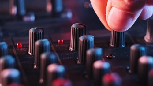 Hand Adjusting Mixing Console Knobs in Studio