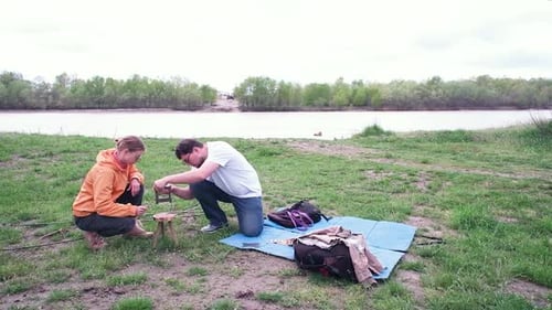 Couple Builds Wooden Structure near River on Green Grass