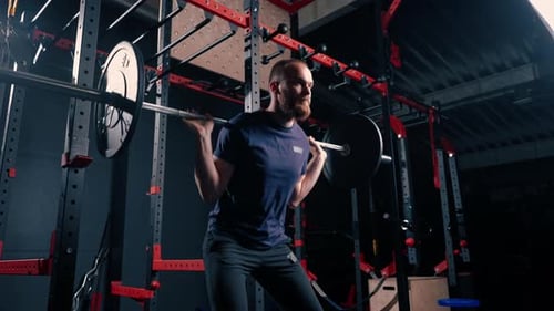 young motivated bodybuilder squatting with heavy barbell in gym exercise active lifestyle body care