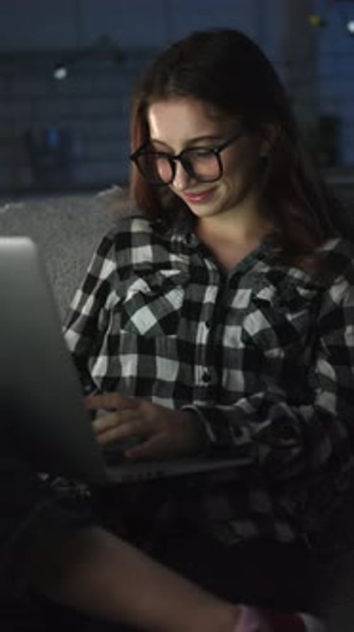 Attractive Young Girl Working On A Laptop At Home In The Night