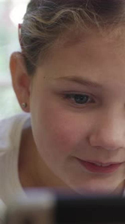Smiling Girl Close Up, looking at Tablet Device
