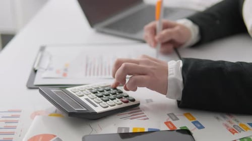 This is an Office Workspace Which Features a Calculator Alongside Various Financial Documents