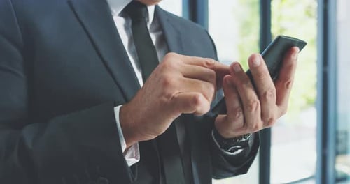 4k video footage of a handsome mature businessman using his cellphone in the office