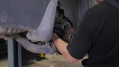 Closeup of a Mechanic Replacing Brake Pads on a Car Wheel at a Service Station