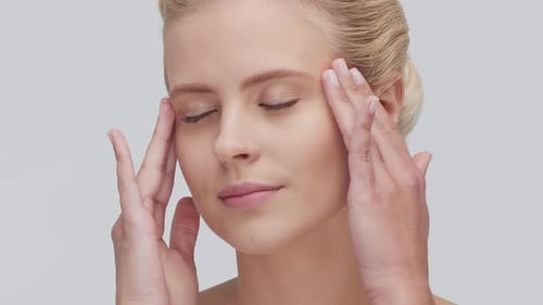 Studio Portrait of Young Beautiful and Natural Blond Woman Applying Skin Care Cream Face Lifting