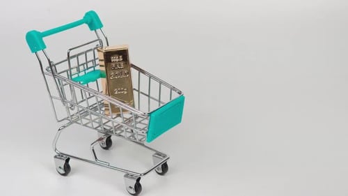 Gold bars in a small shopping cart symbolizing wealth, investment