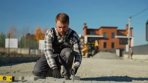 Construction Worker Fitting Paving Stones into Place