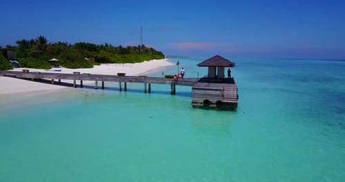 vista de perto de um deck de madeira no mar azul-turquesa nas Maldivas, enquanto um pessoal espera por um menino