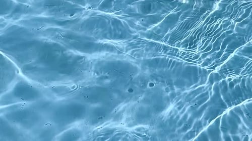 Reines blaues Wasser im Pool mit Sonnenlichtreflexen.