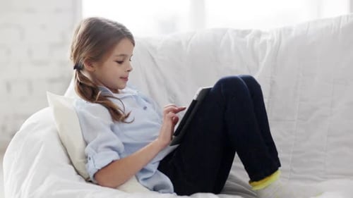 Little student girl happily learning with tablet pc at home on the internet