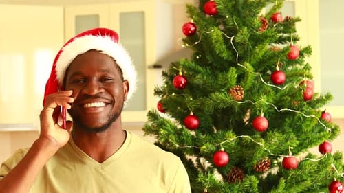 Smiling Man Talking on Phone By Christmas Tree