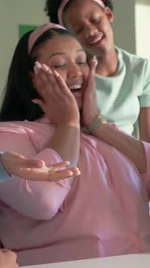 Showing teacher in pink shirt and headband pointing at tablet at classroom table, engaging children