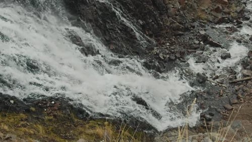 A Cascade of Waterfalls Cascades Down Crashing Against Dark Rocks