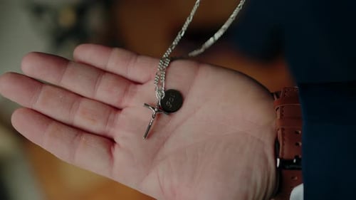 Adult Holds Cross Necklace in Close Up Shot