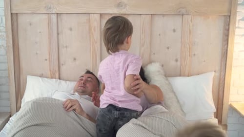 Happy Family Playfully Interacts on Bed in Cozy Home