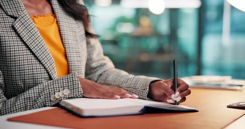Woman Writing in Notebook at Desk in Office