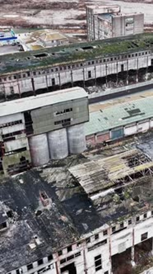 Neglected locality of a past time plant. Abandoned ruins of warehouses with broken walls