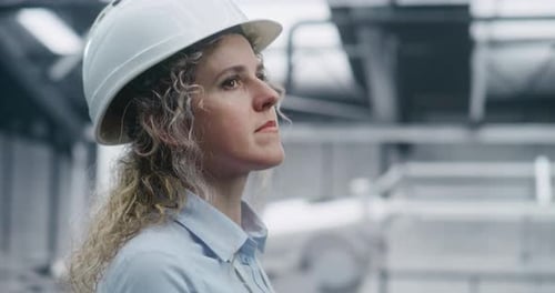 Spécialiste technique féminine portant une chemise et un badge d'identification supervisant le processus d'assemblage robotique