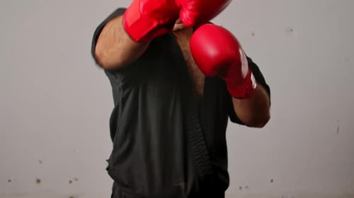 Man in Karate Gi Practicing Punching with Boxing Gloves