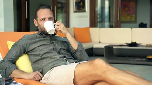 Man Relaxing, Lounging with Coffee Outside Modern Home